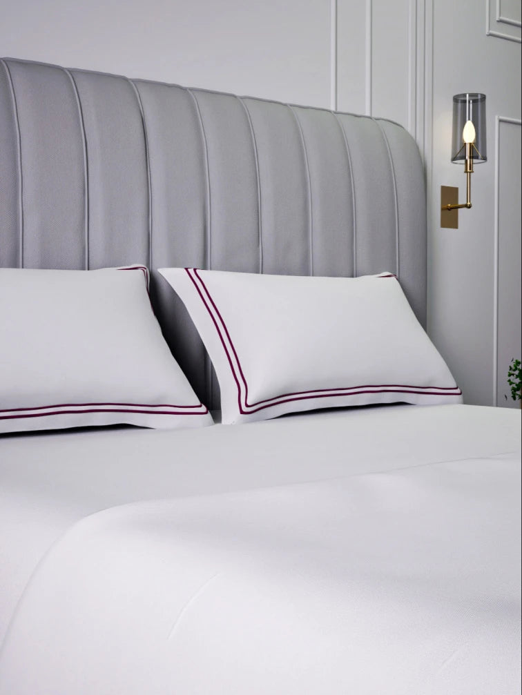 Gray upholstered bed with sovereign white bedding with double Mulberry color marrowing in a bedroom setting