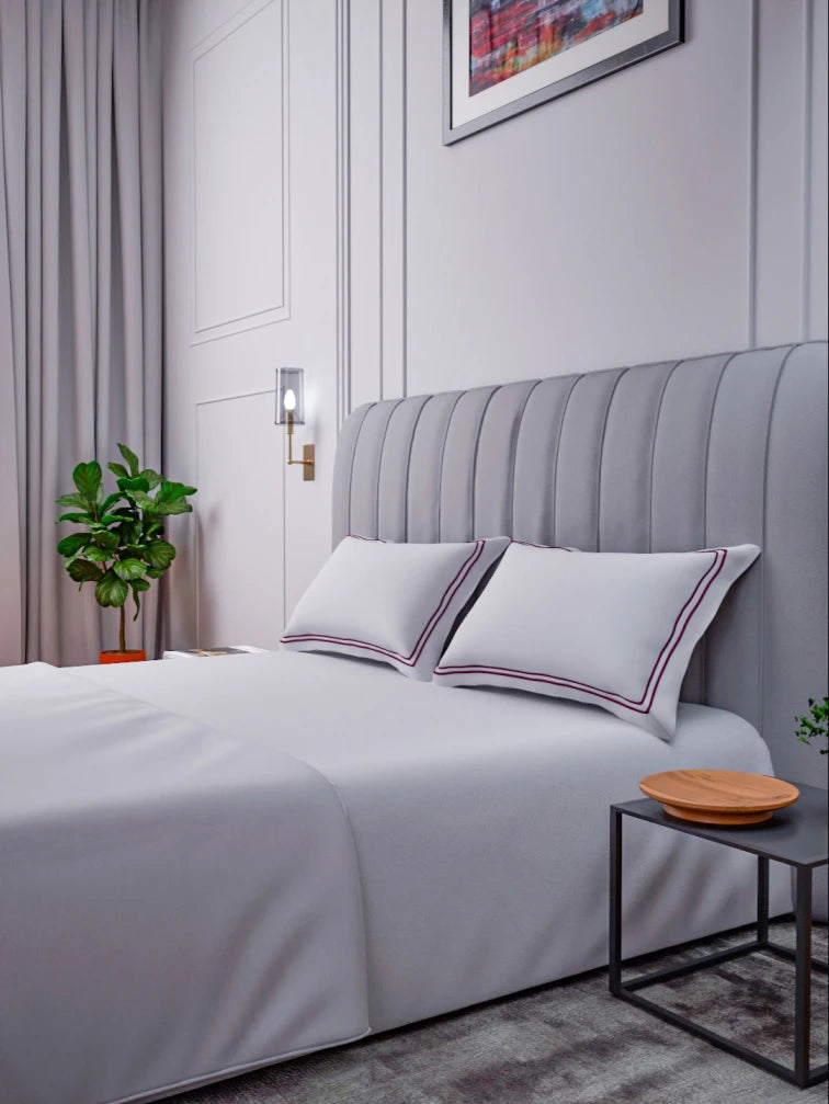 Gray upholstered bed with sovereign white bedding with double Mulberry color marrowing in a bedroom setting