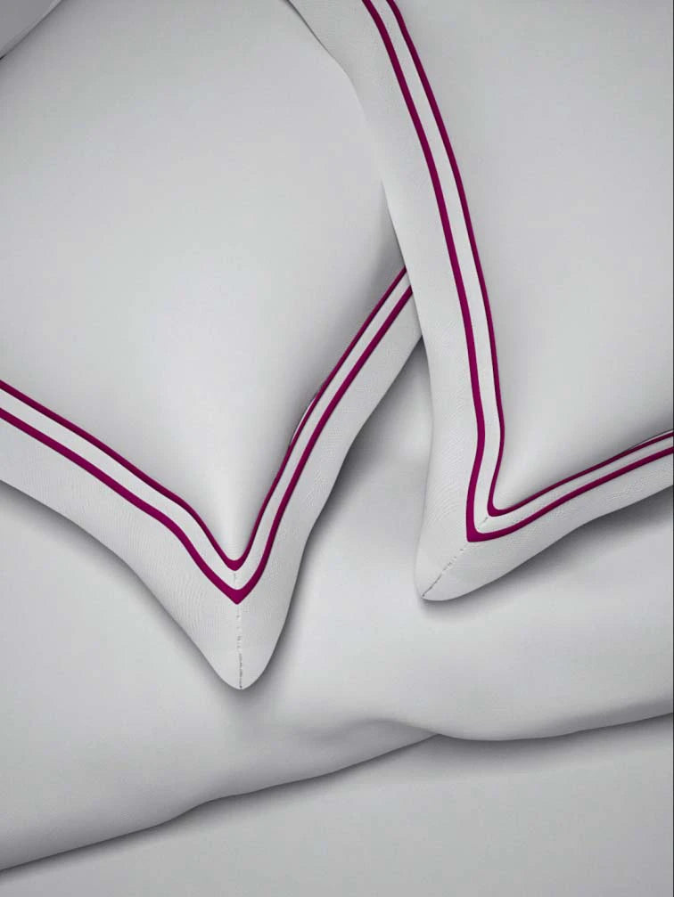 Two sovereign white pillows  with double Mulberry color marrowing in a bedroom setting