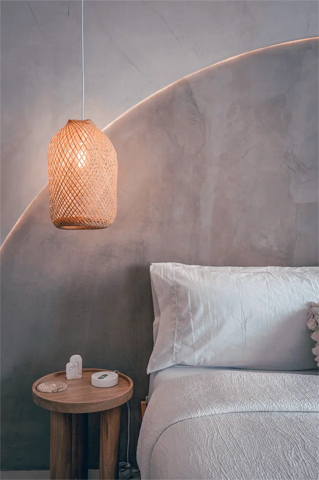 Woven pendant light hanging above a bed with white mulberry living bedding 